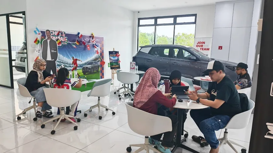 Visitors at a Chery Kluang showroom event beside a displayed SUV.