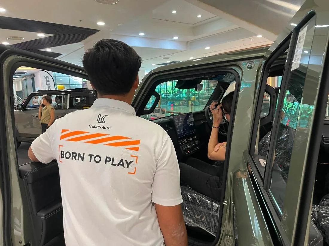A Li Koon Auto salesperson in a Born to Play polo shirt showing a customer the V23 interior